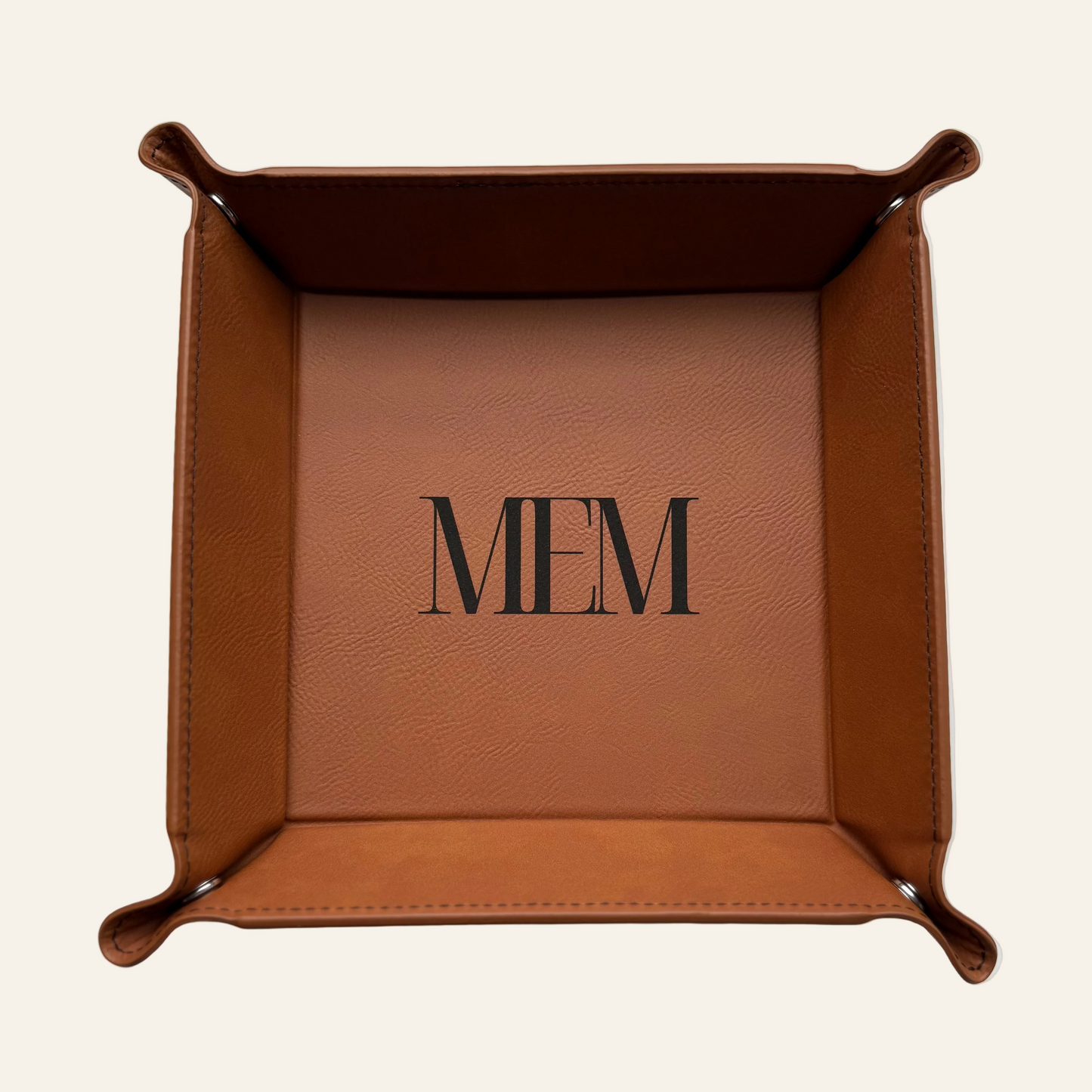 Brown leather tray with monogram on a white surface